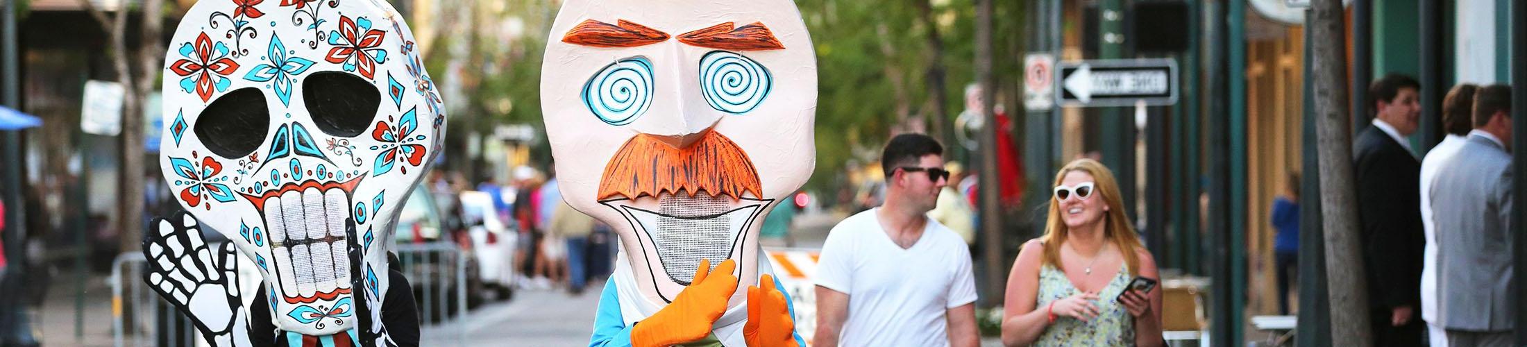 Two people walking with people in costumes at music festival